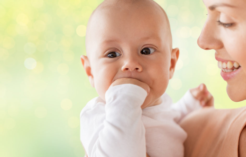 happy mother with little baby boy sucking fingers